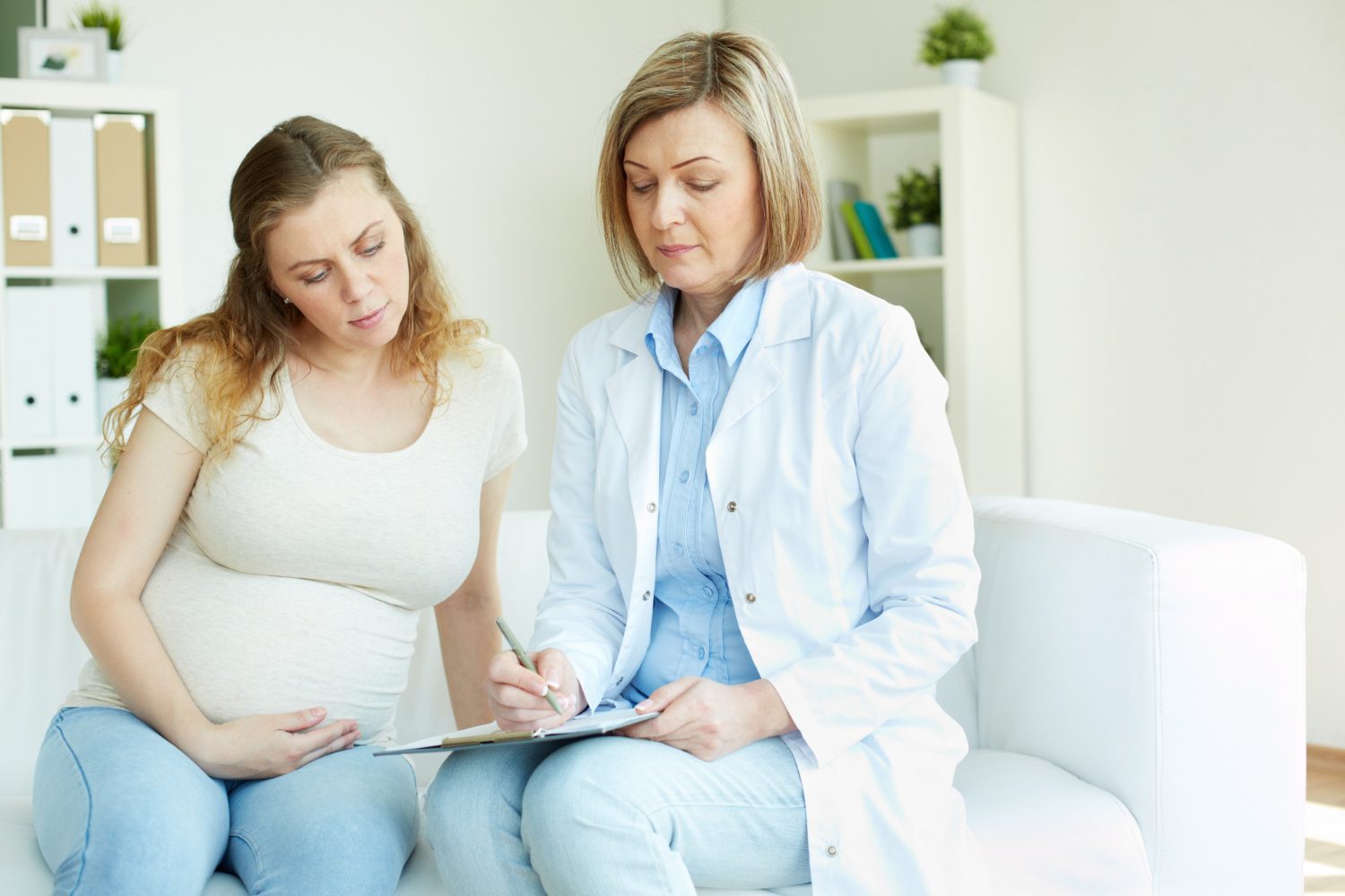 pregnant woman talking to her doctor in a room pregnant woman talking to her doctor in a room